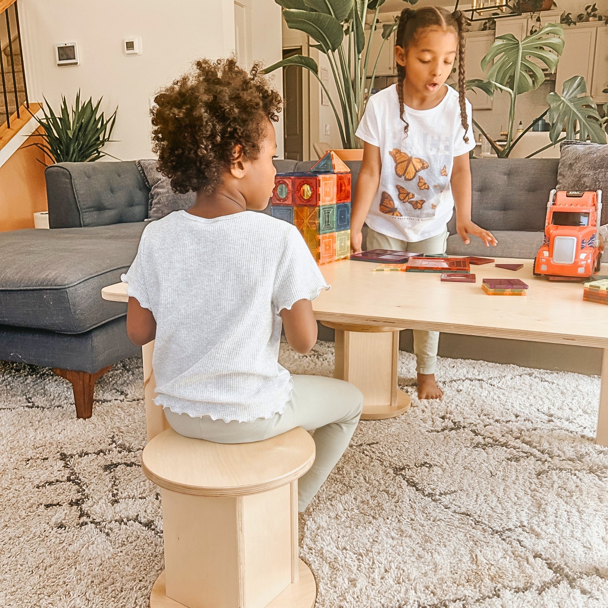 Two children playing with toys on a coffee table in a living room.