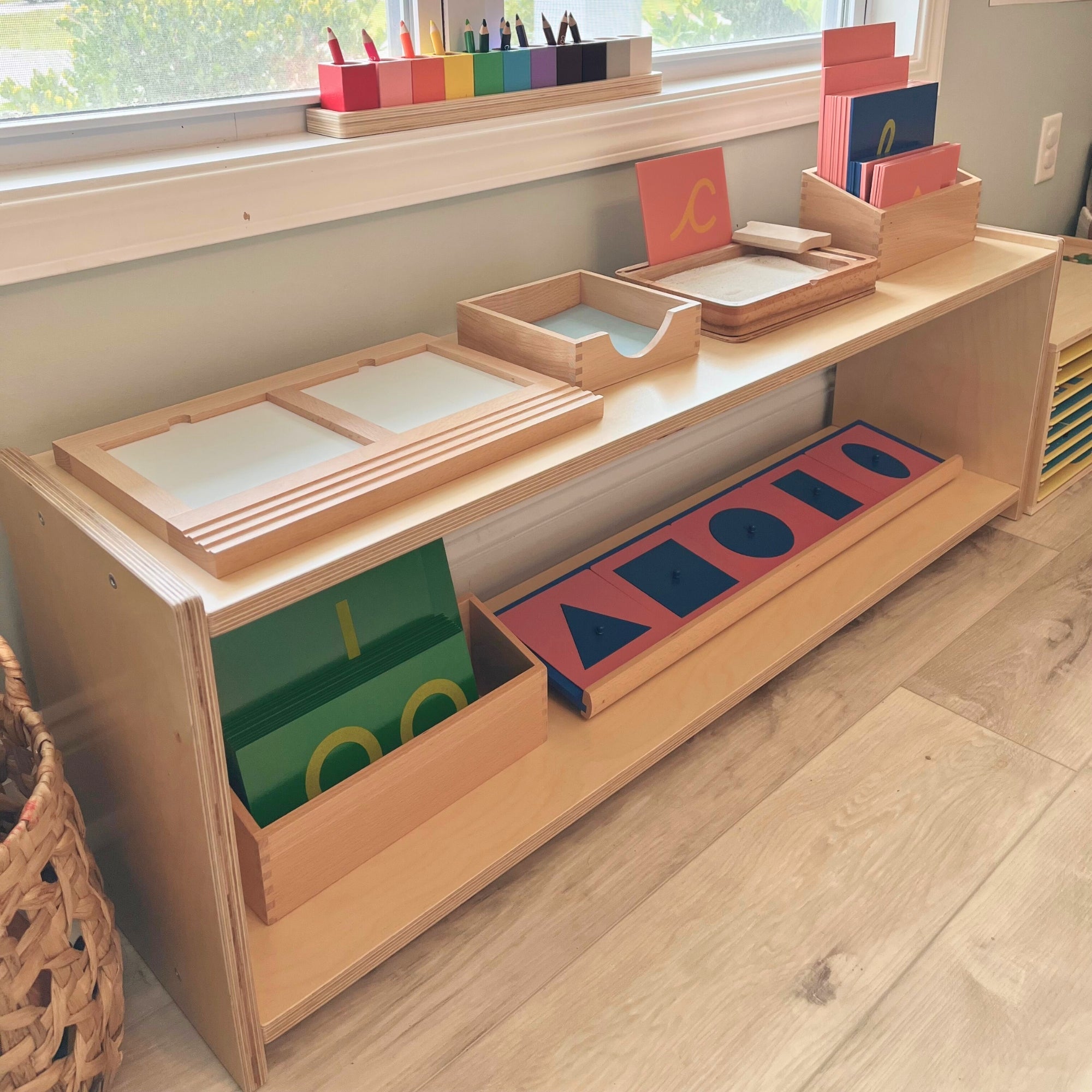 Wooden educational shelf with colorful geometric shapes and books in a classroom setting.