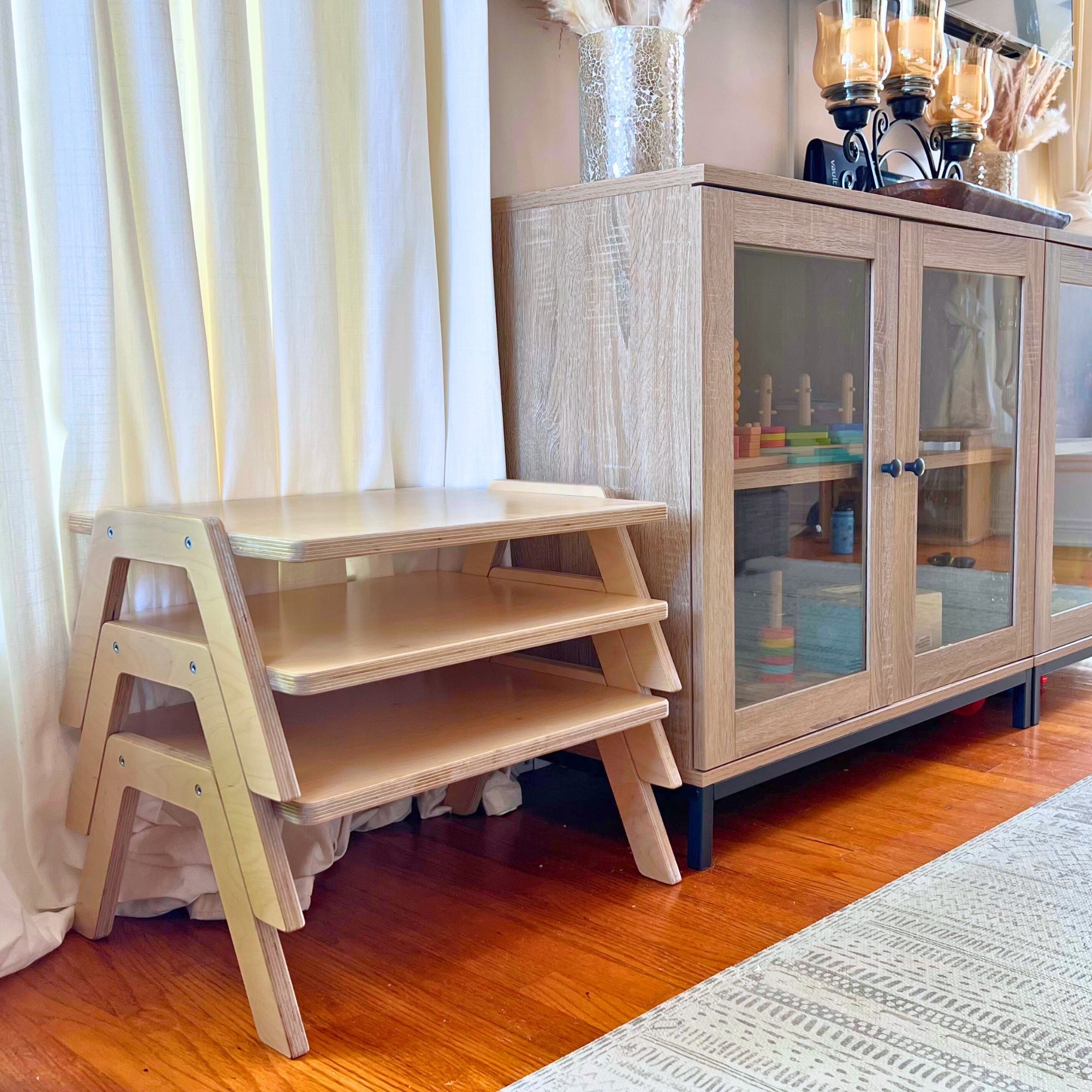 Wooden step stool in a room with a cabinet and curtains.