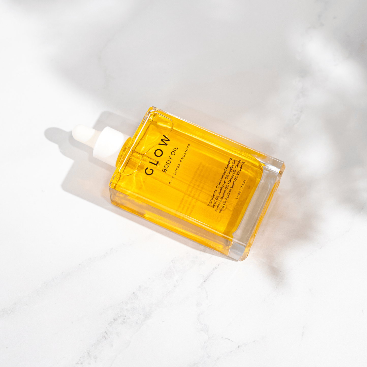 Yellow bottle of Glow Body Oil on a white background