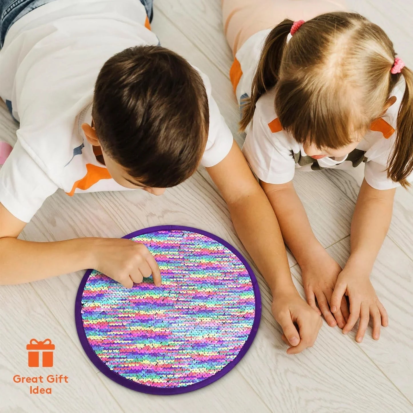 Two children playing with a round rainbow sequin sensory fidget pad on a wooden floor