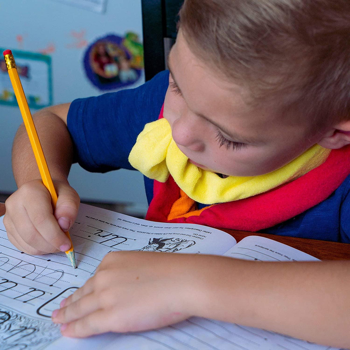 Child wearing a sensory chew necklace writing in a handwriting workbook