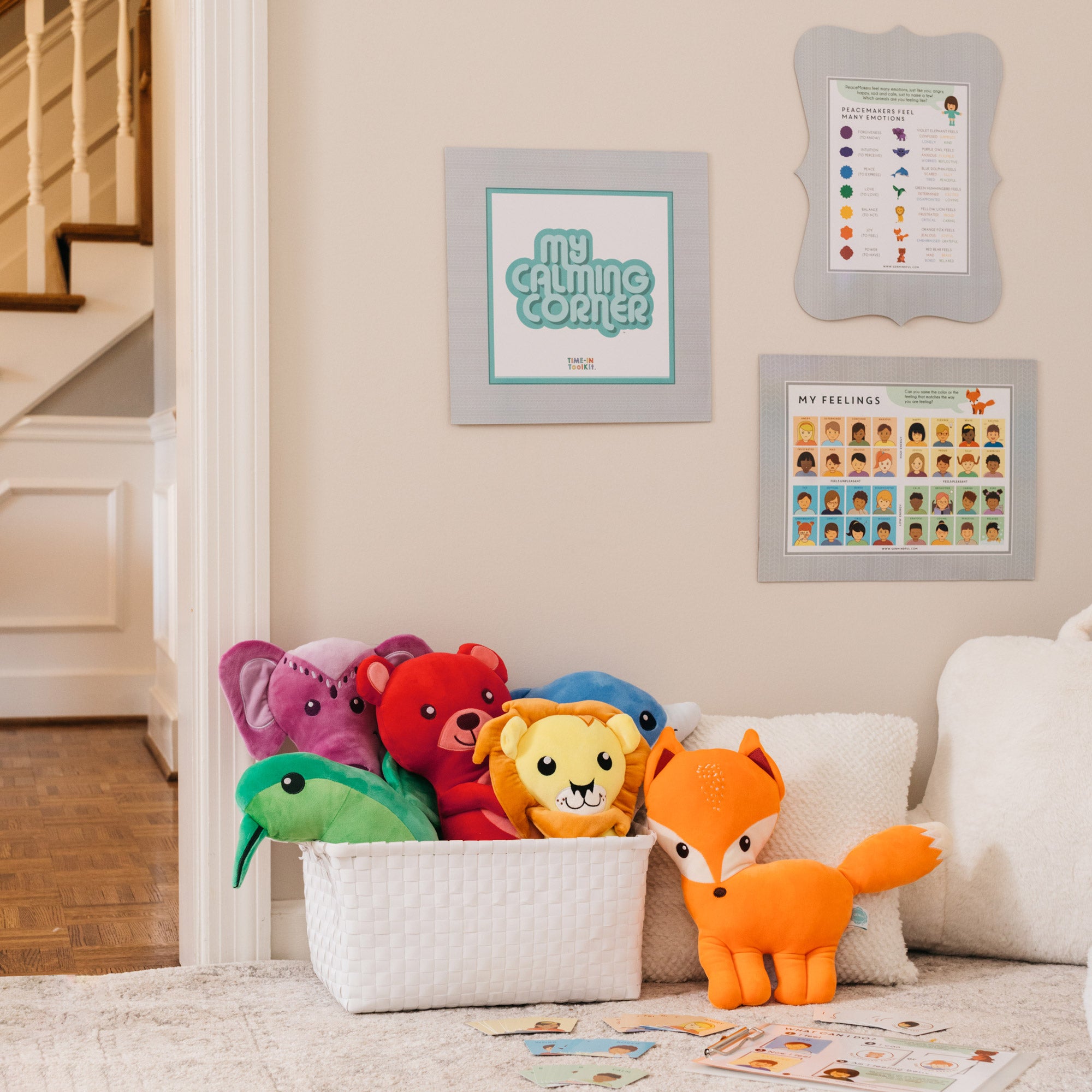 Colorful stuffed animals in a basket with educational posters on the wall in a home setting.