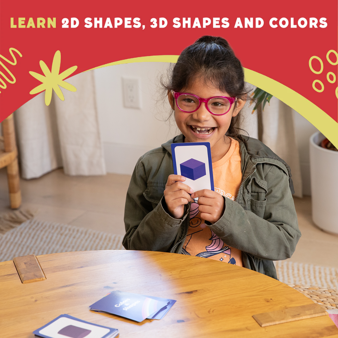 Child holding a card with a shape on it, learning shapes and colors in a home setting.