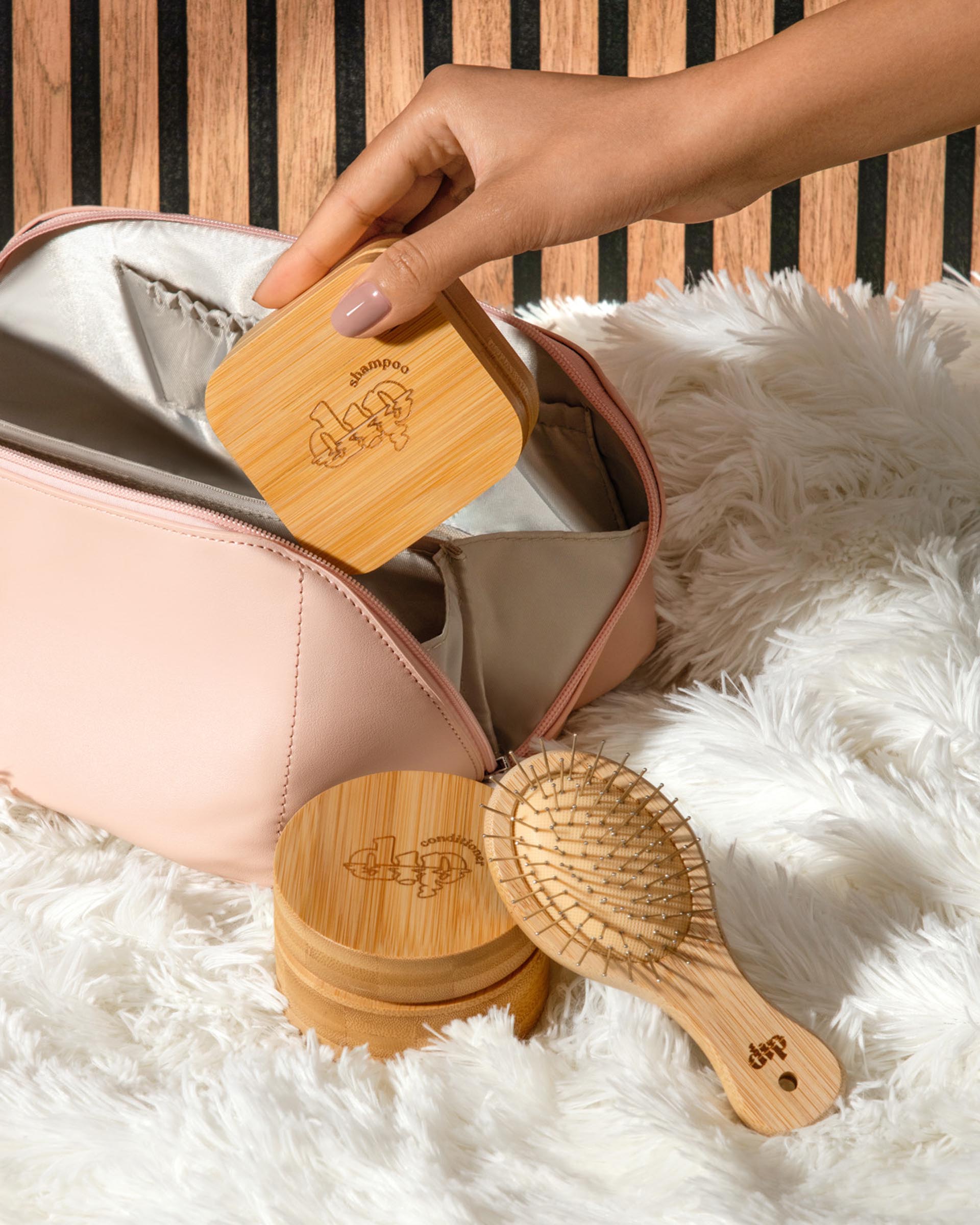 Hand holding a wooden brush with 'dodo' branding on a fluffy white surface.