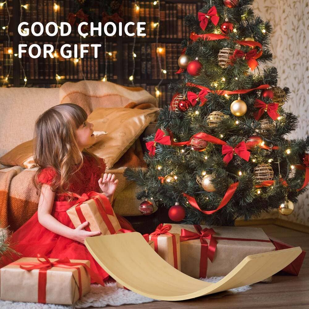Child in a red dress opening a gift near a decorated Christmas tree.