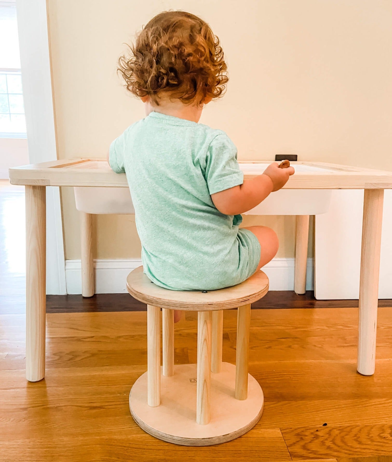 Child sitting on a wooden stool at a table indoors