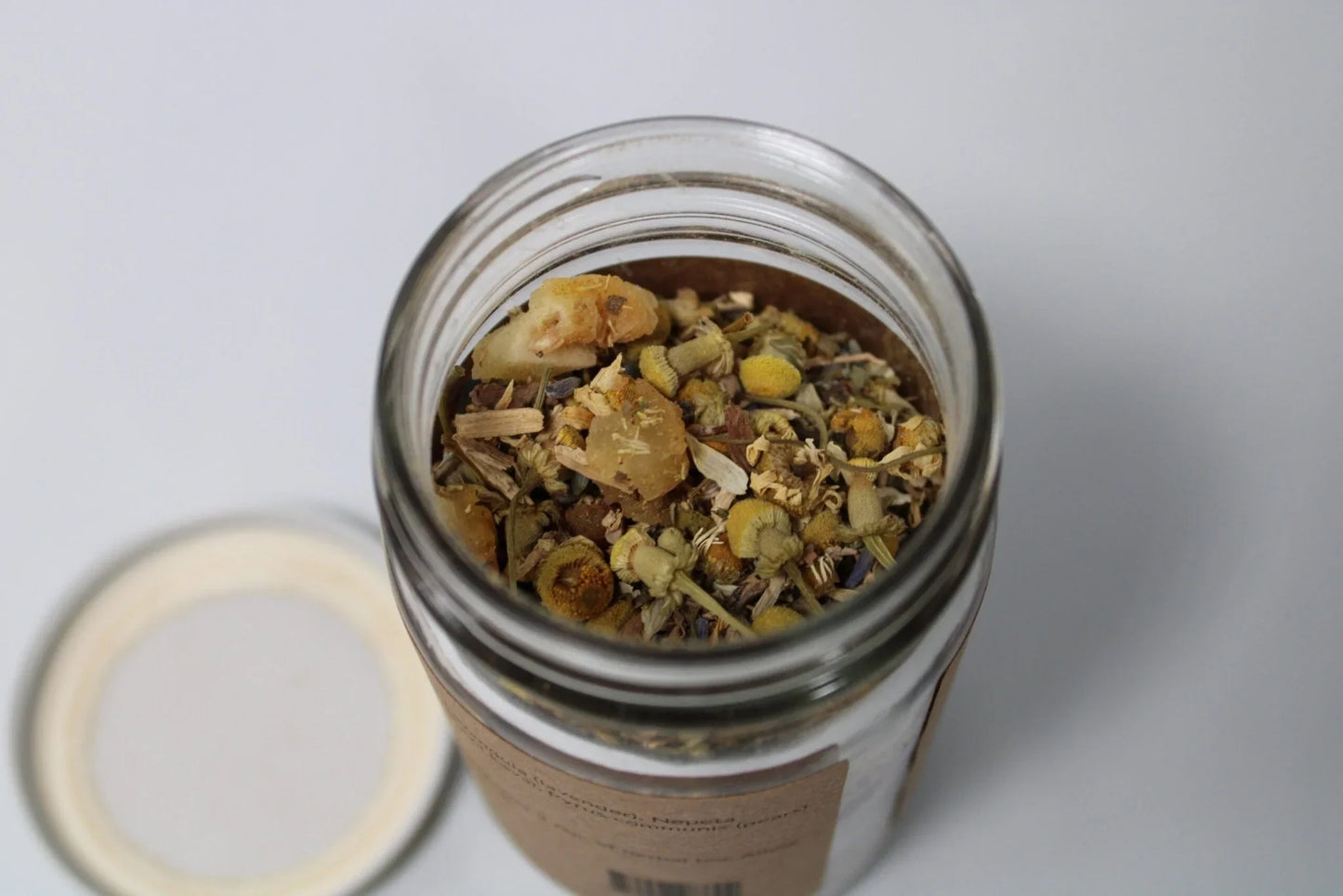Glass jar filled with loose leaf herbal tea blend featuring chamomile and dried herbs