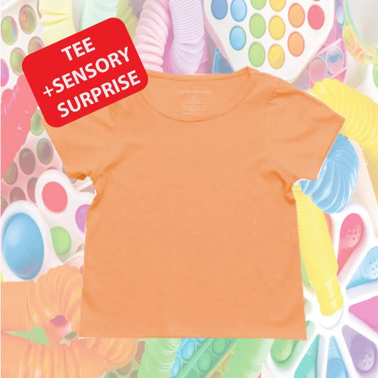 Coral sensory-friendly kids tee with 'TEE + SENSORY SURPRISE' text, surrounded by colorful fidget toys.