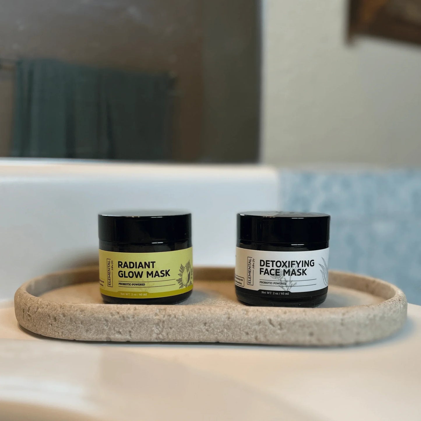 Detoxifying face mask and radiant glow mask jars on a bathroom counter tray