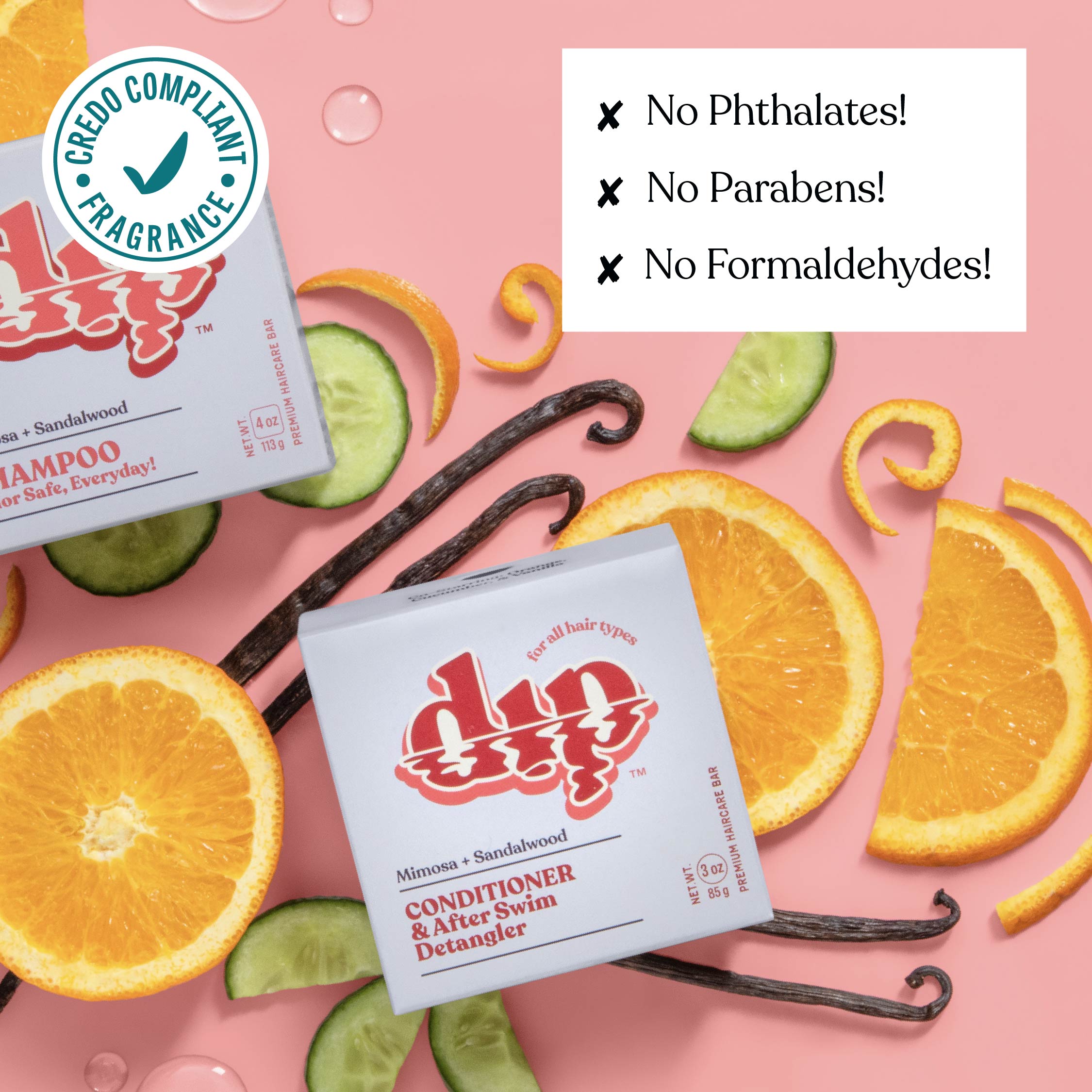 Dip shampoo and conditioner packaging with oranges, cucumbers, and vanilla beans on a pink background.