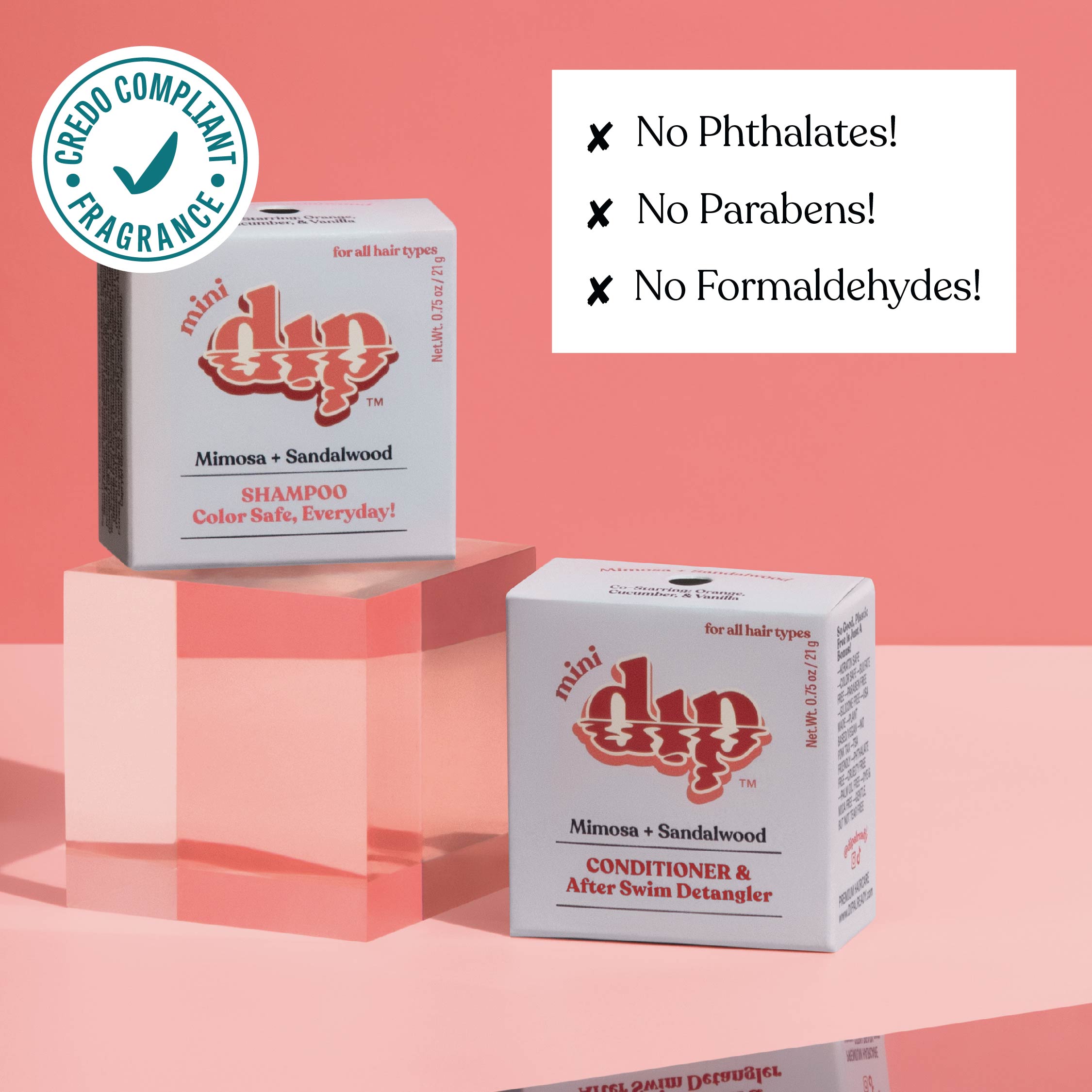Two boxes of mini dip shampoo and conditioner on a pink background with greenery.