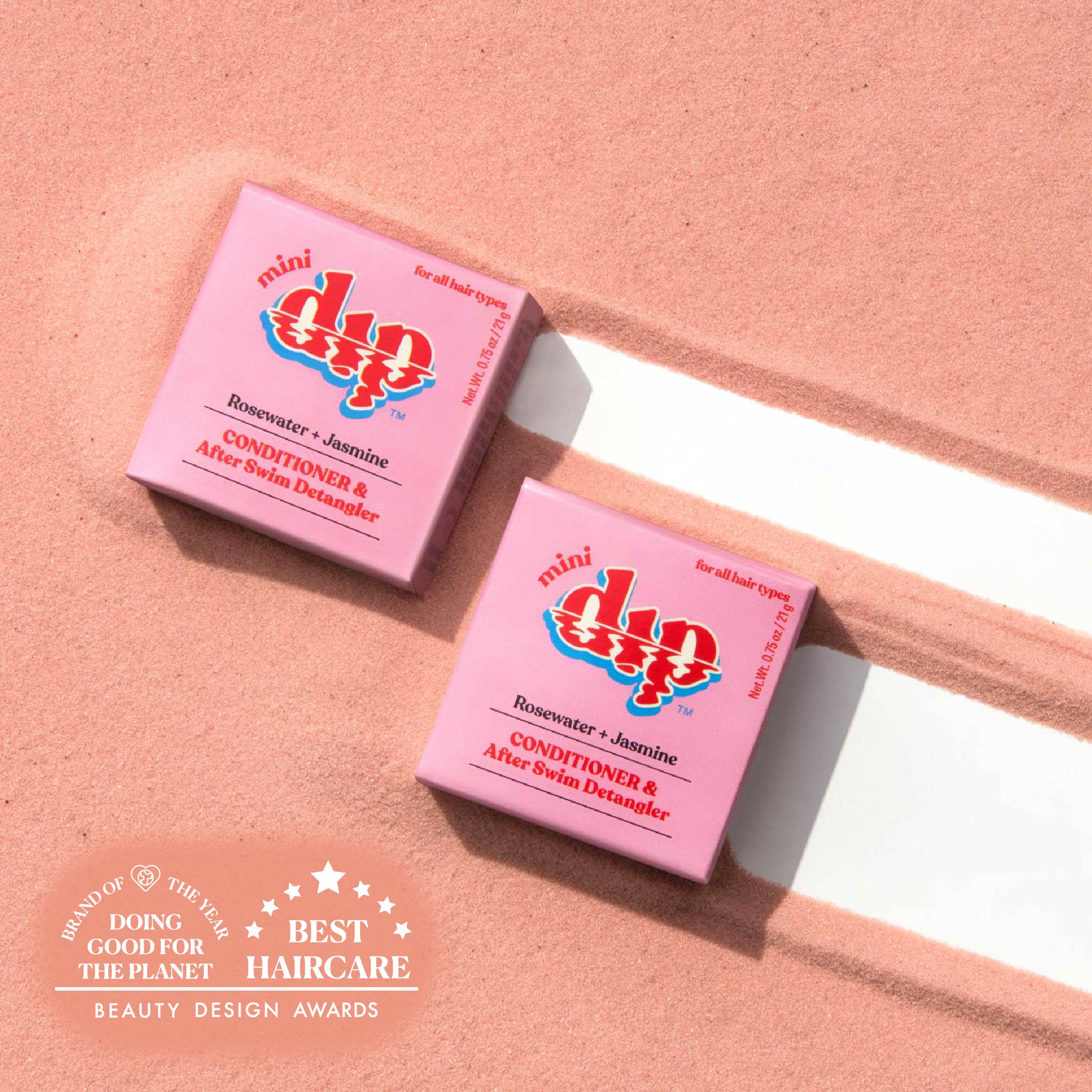 Two pink boxes of 'mini dip' hair care product on a peach background with awards text.