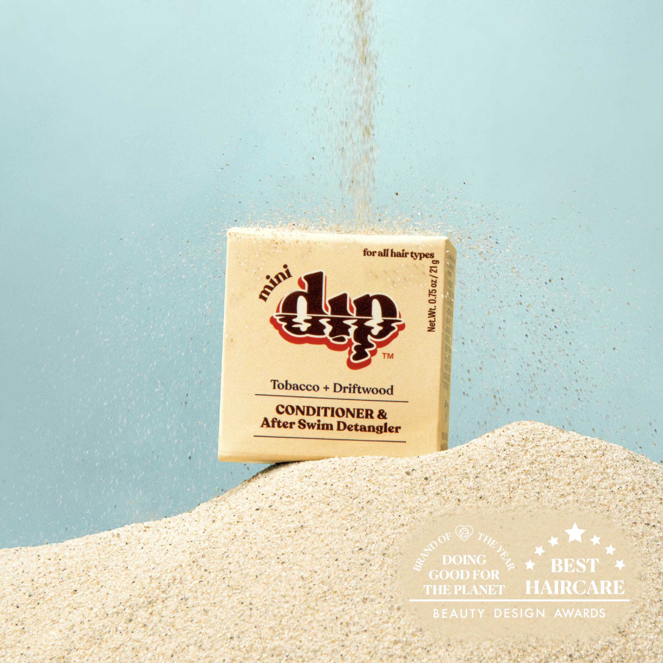 Bar of soap with a box labeled 'dip' on a sandy surface with a light blue background