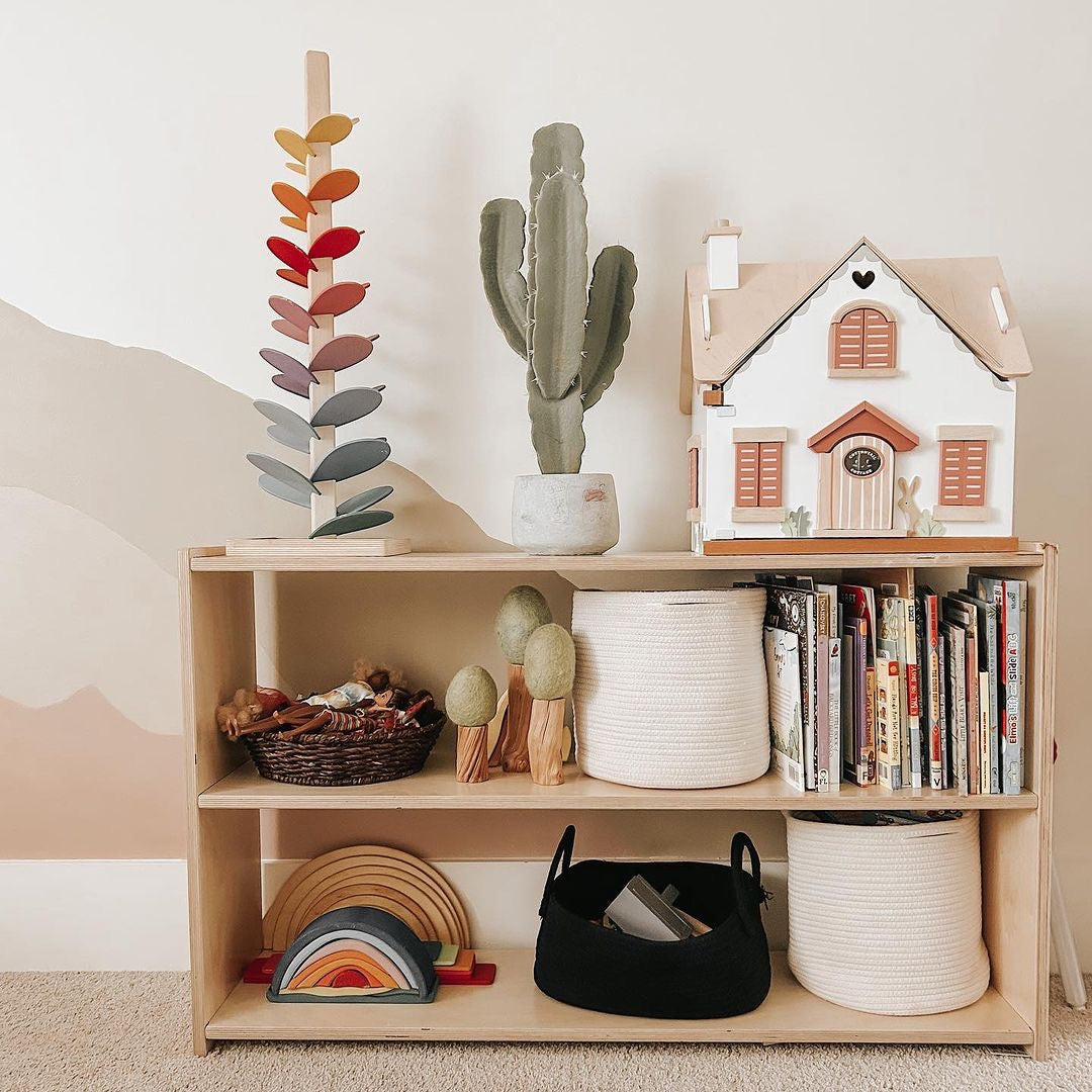 Wooden shelf with toys, books, and decorative items against a plain wall.