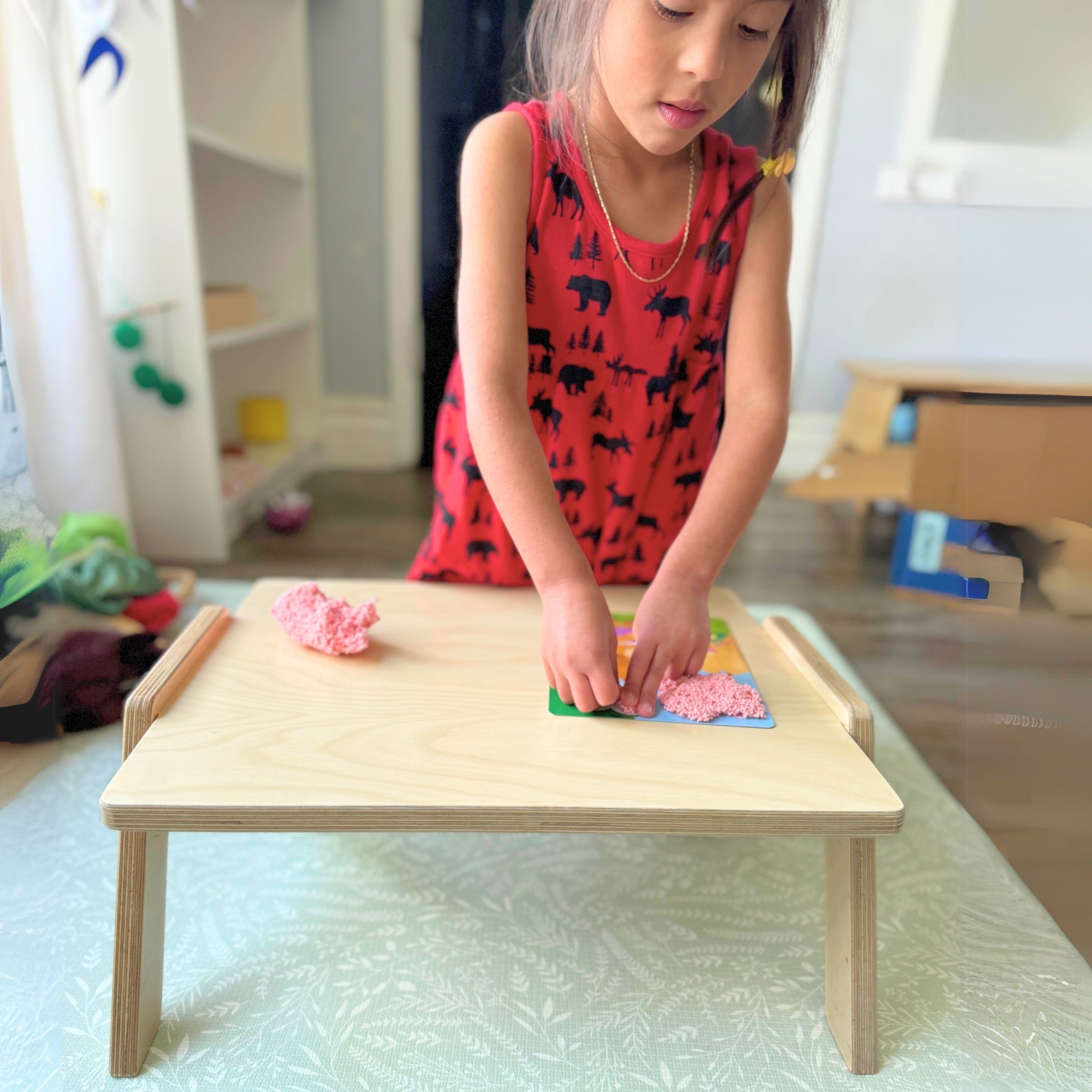Child playing with colorful blocks on a small wooden table in a room.