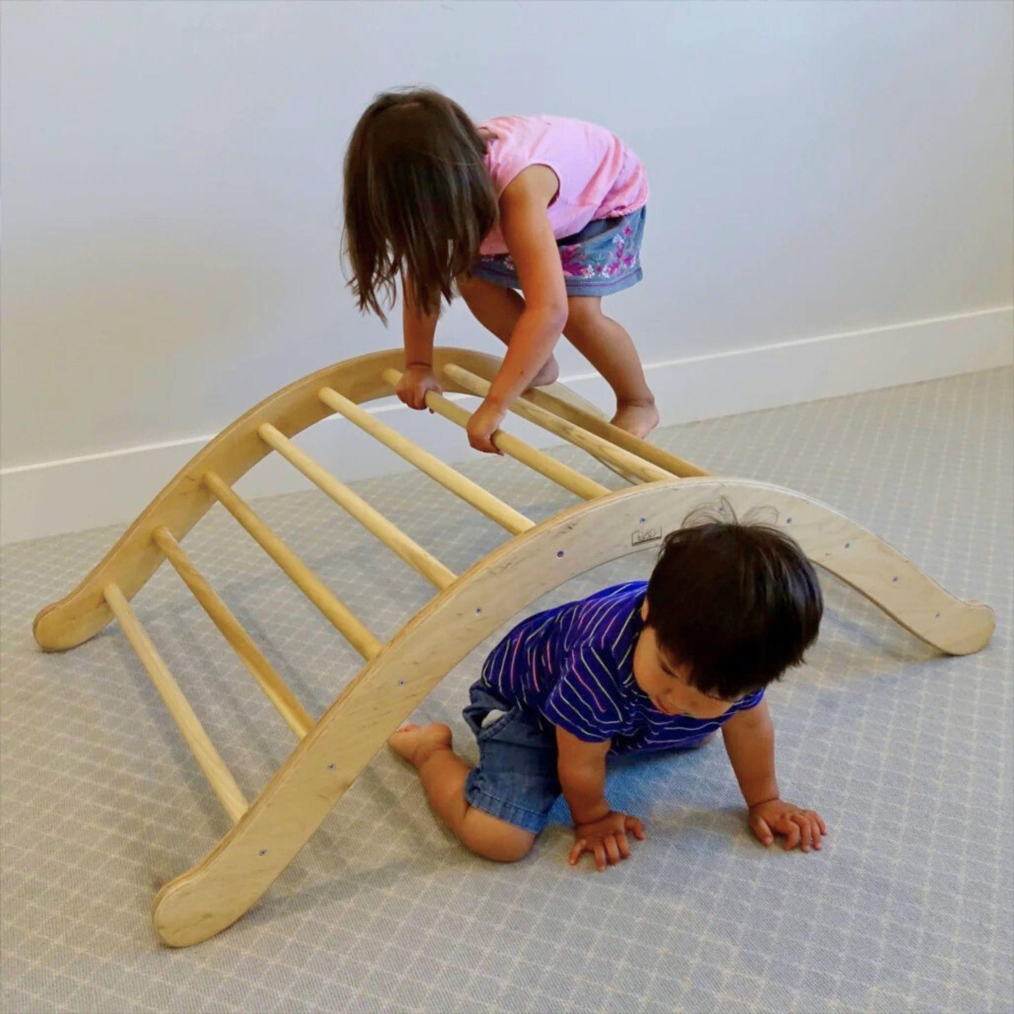 Two children playing on a wooden climbing toy indoors.