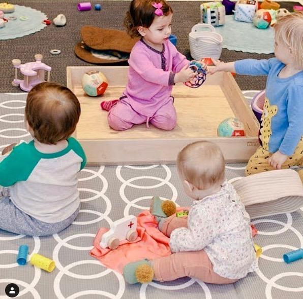 Toddlers playing on a Pikler crawling platform with sensory toys in a sensory-friendly playroom