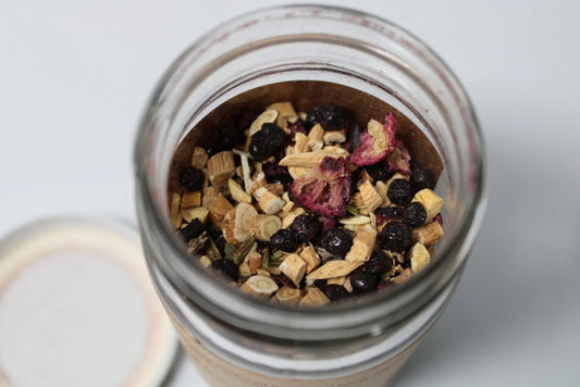 Loose leaf herbal tea blend with dried organic herbs and berries in a glass jar