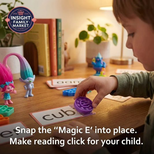 Child playing reading game with word cards, pop-it toy, and colorful trolls on a wooden desk.