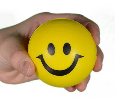 Hand holding a yellow smiley face stress ball, sensory toy for anxiety or focus support
