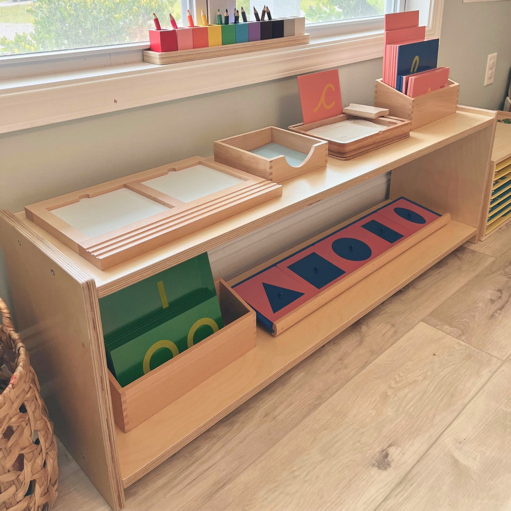 Wooden educational shelf with colorful geometric shapes and books in a classroom setting.