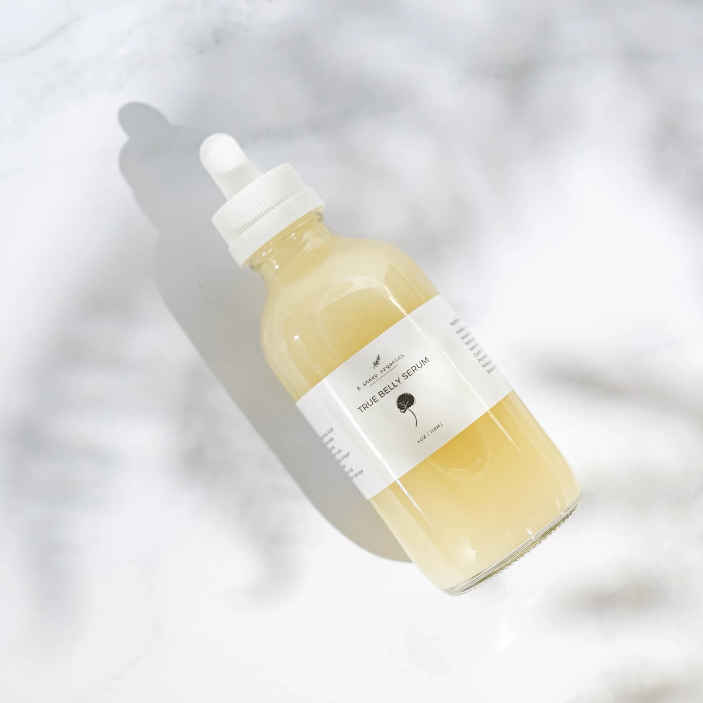 Glass dropper bottle of True Belly Serum on white background, skincare wellness product