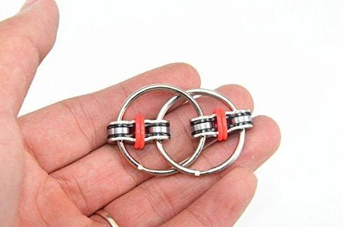 Hand holding two metal fidget rings with red silicone bands, sensory toy for focus and stress relief