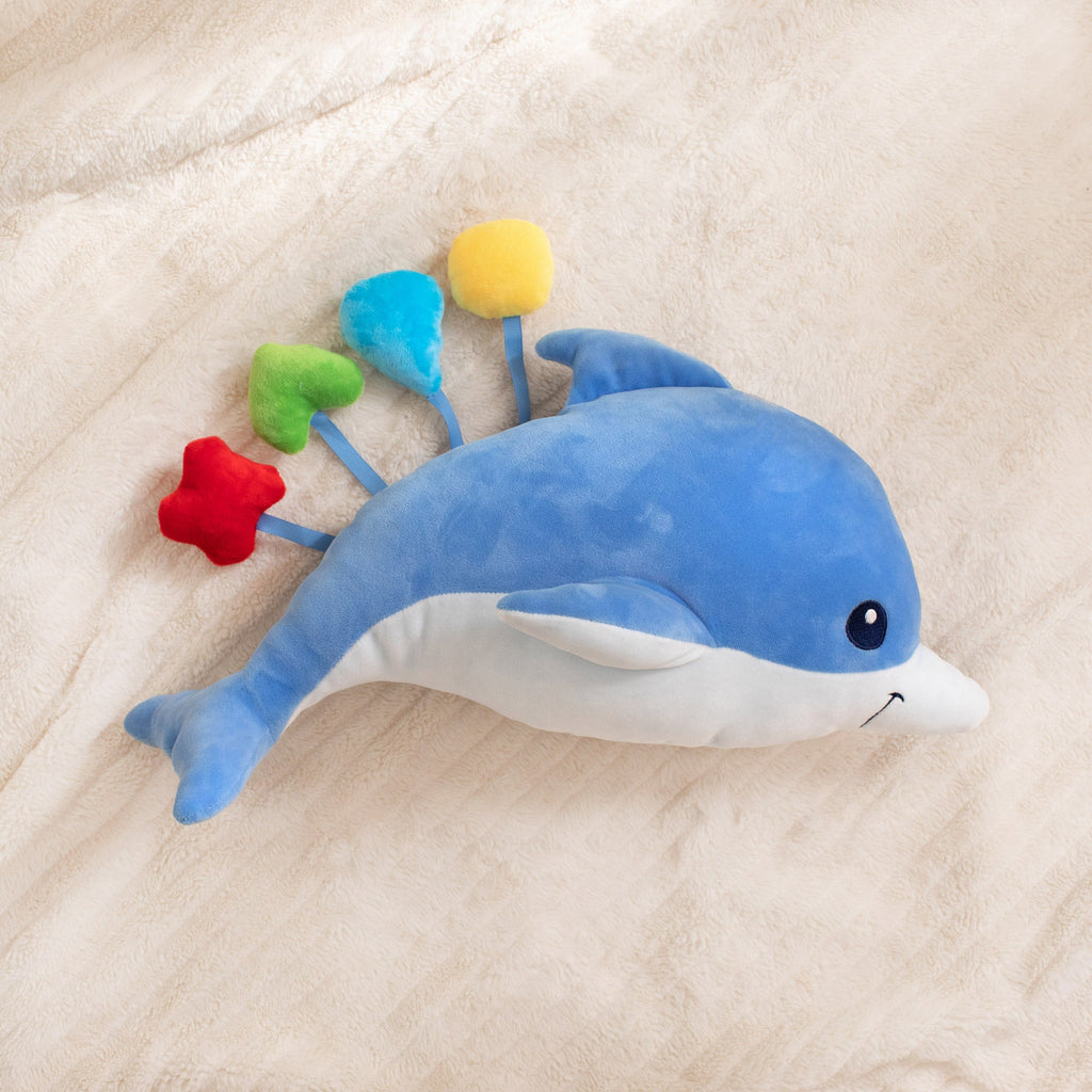 Blue dolphin plush toy with colorful flowers on a beige blanket
