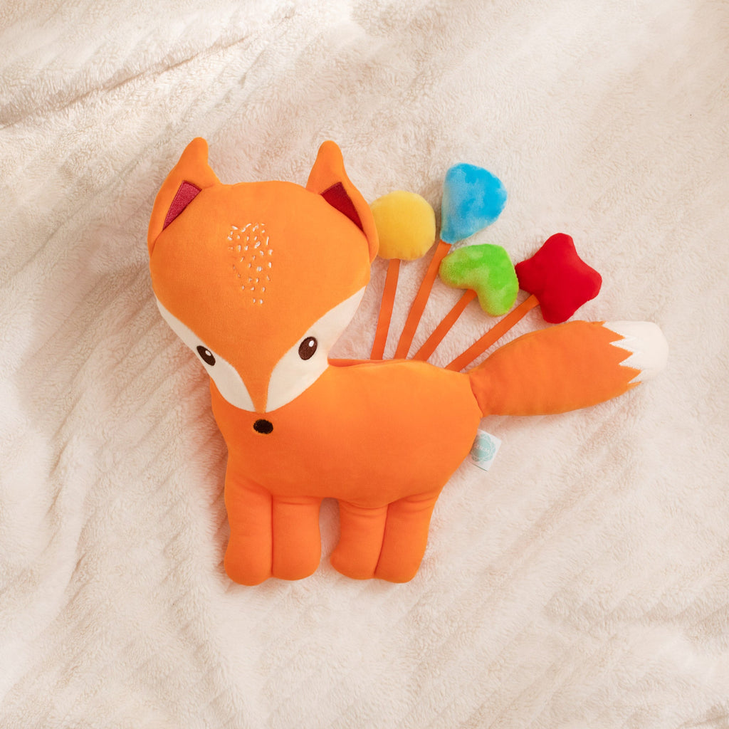 Plush fox toy with colorful stars on a soft beige background