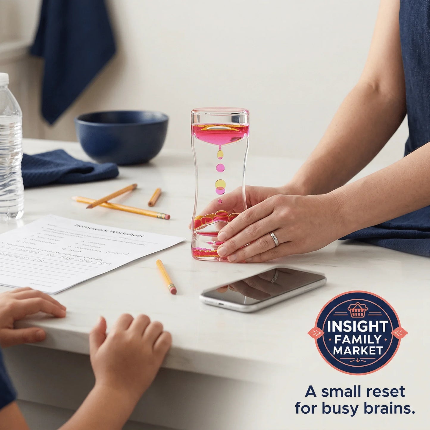 Adult holds pink sensory timer on desk with pencils, worksheet, and child, supporting focus