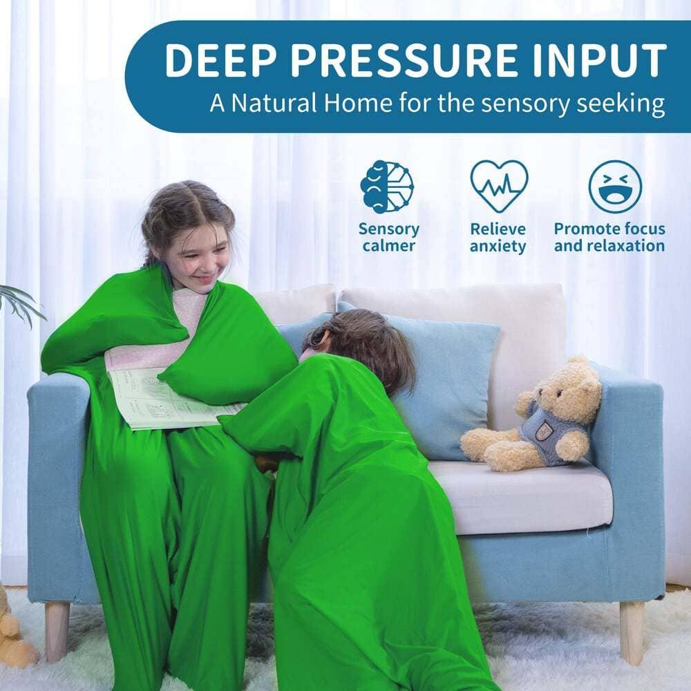 Children using a green sensory compression blanket for deep pressure comfort on a couch.