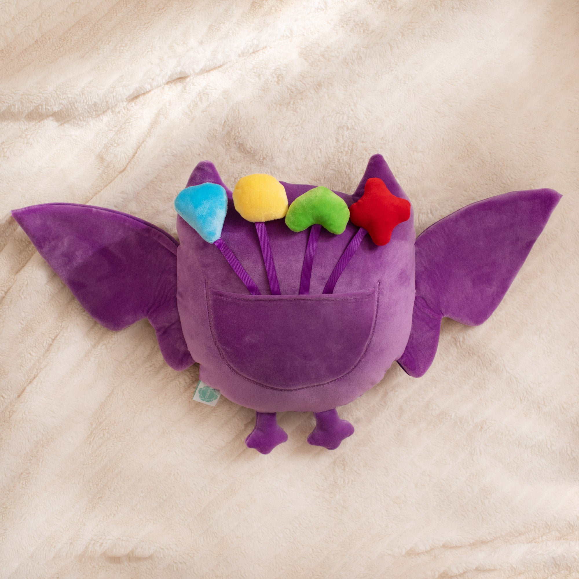 Purple plush toy with colorful accents on a beige surface