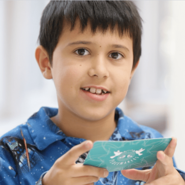 Child holding a green card with a blurred background