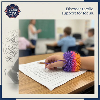 Child in classroom wearing colorful sensory bracelet for focus while working on worksheet
