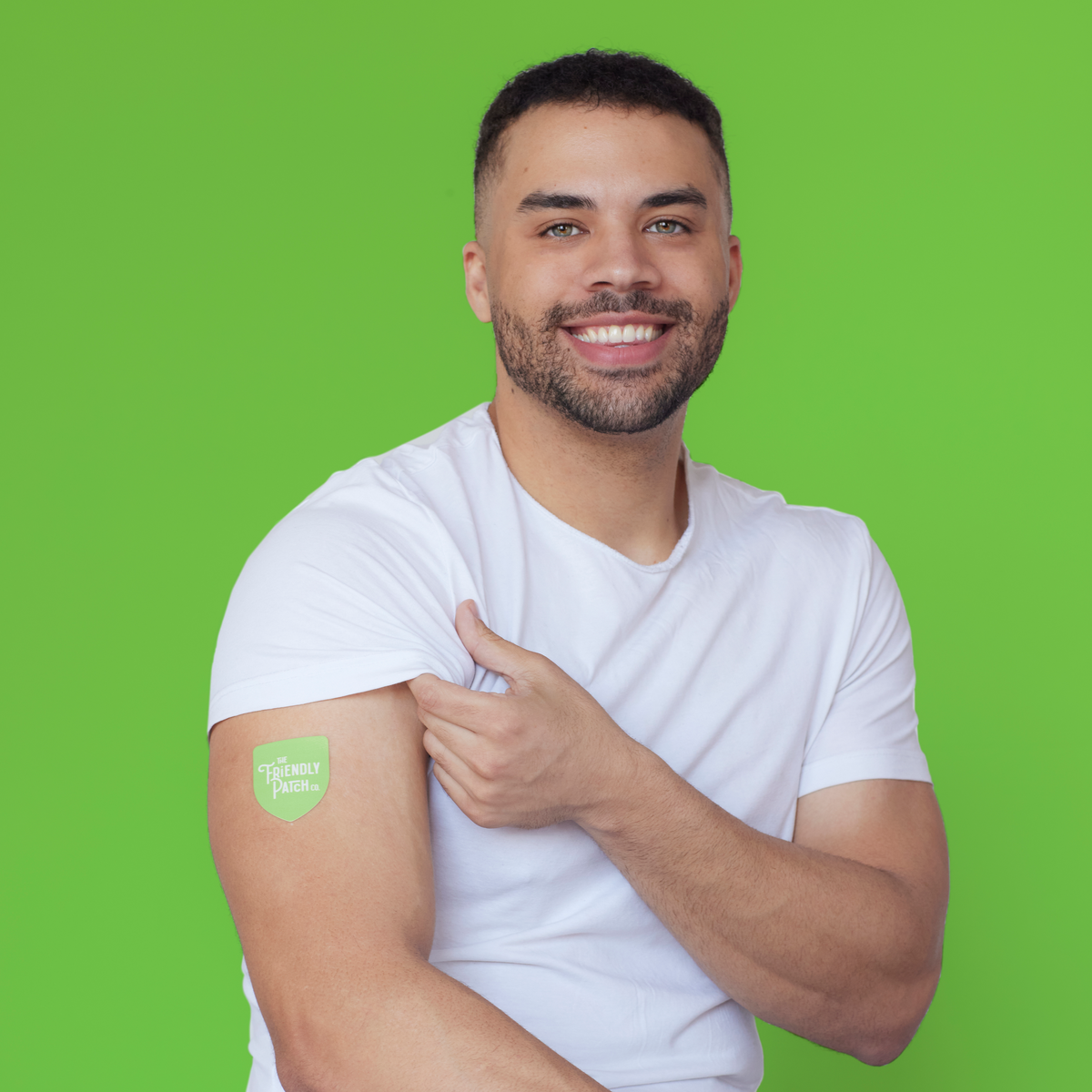 Man wearing a white t-shirt with a green patch on his arm against a green background