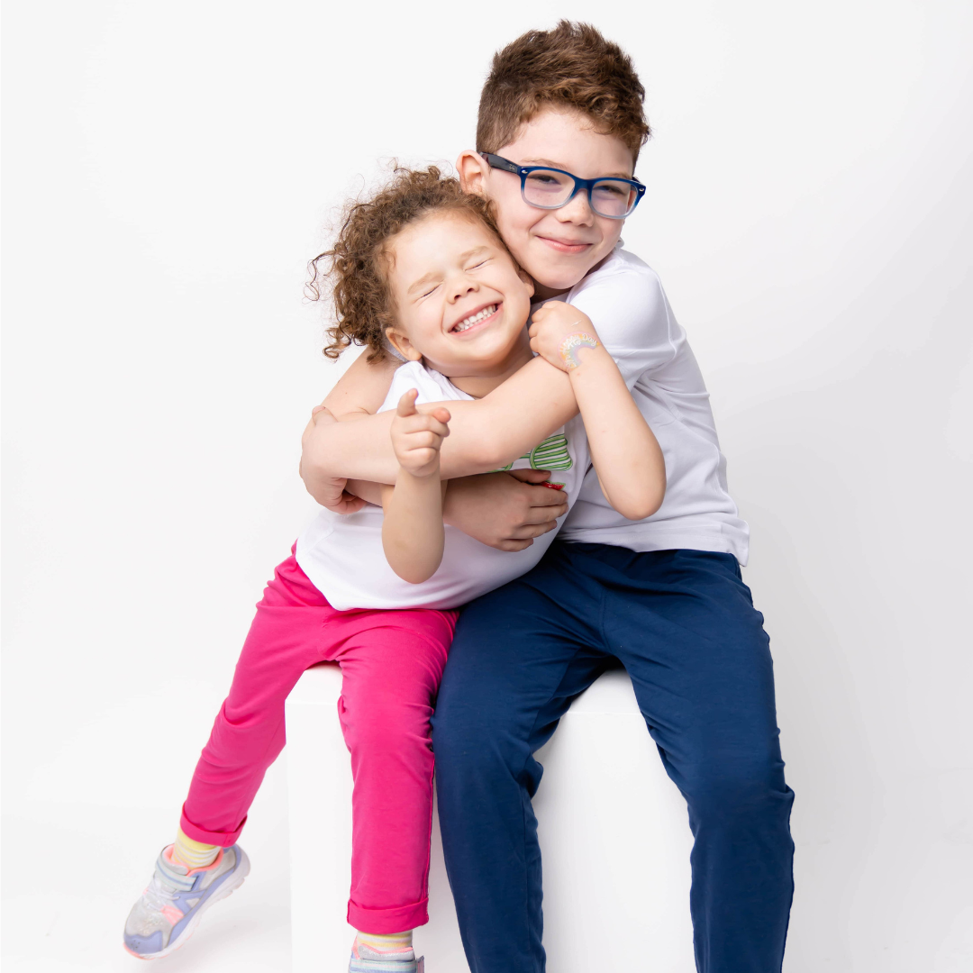 Two children hugging each other on a white background