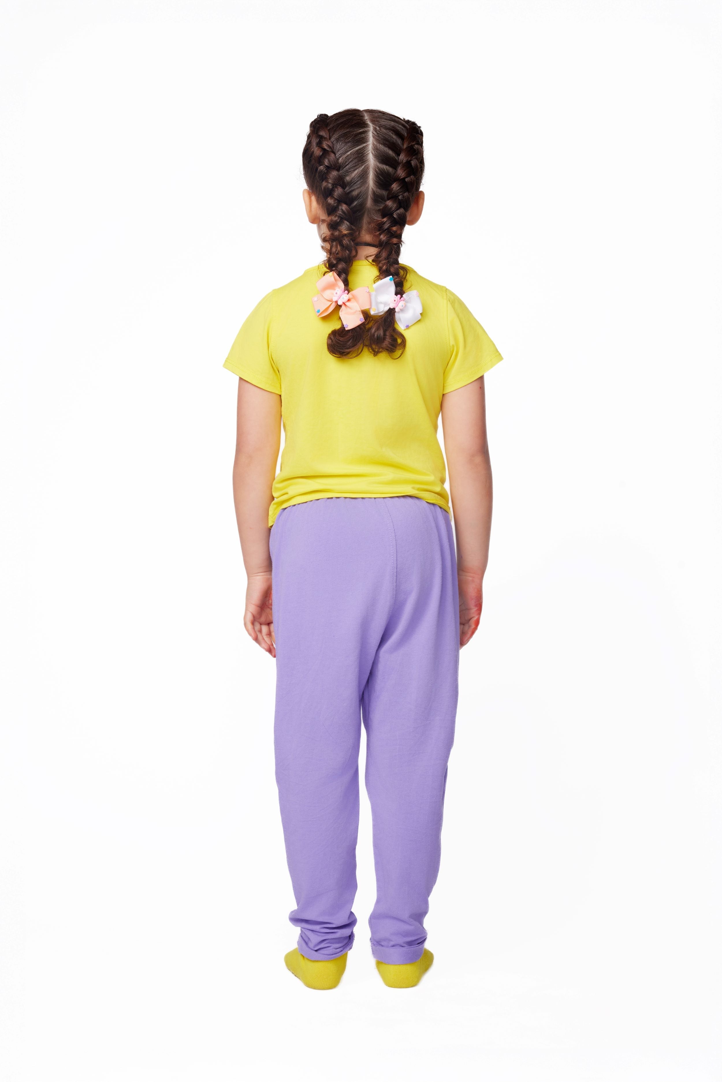 Child wearing a yellow shirt and purple pants on a white background