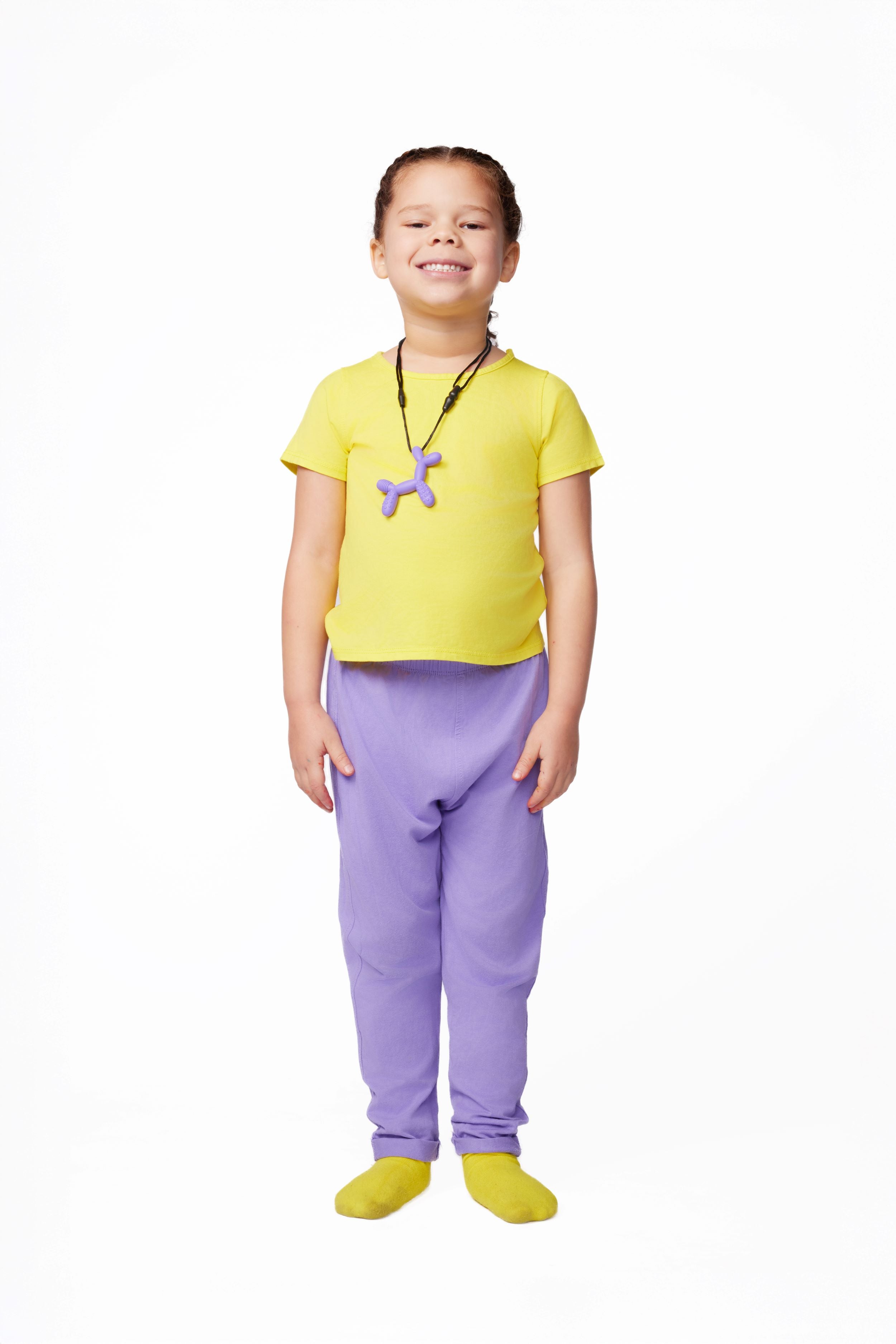 Child wearing a yellow shirt, purple pants, and yellow shoes on a white background