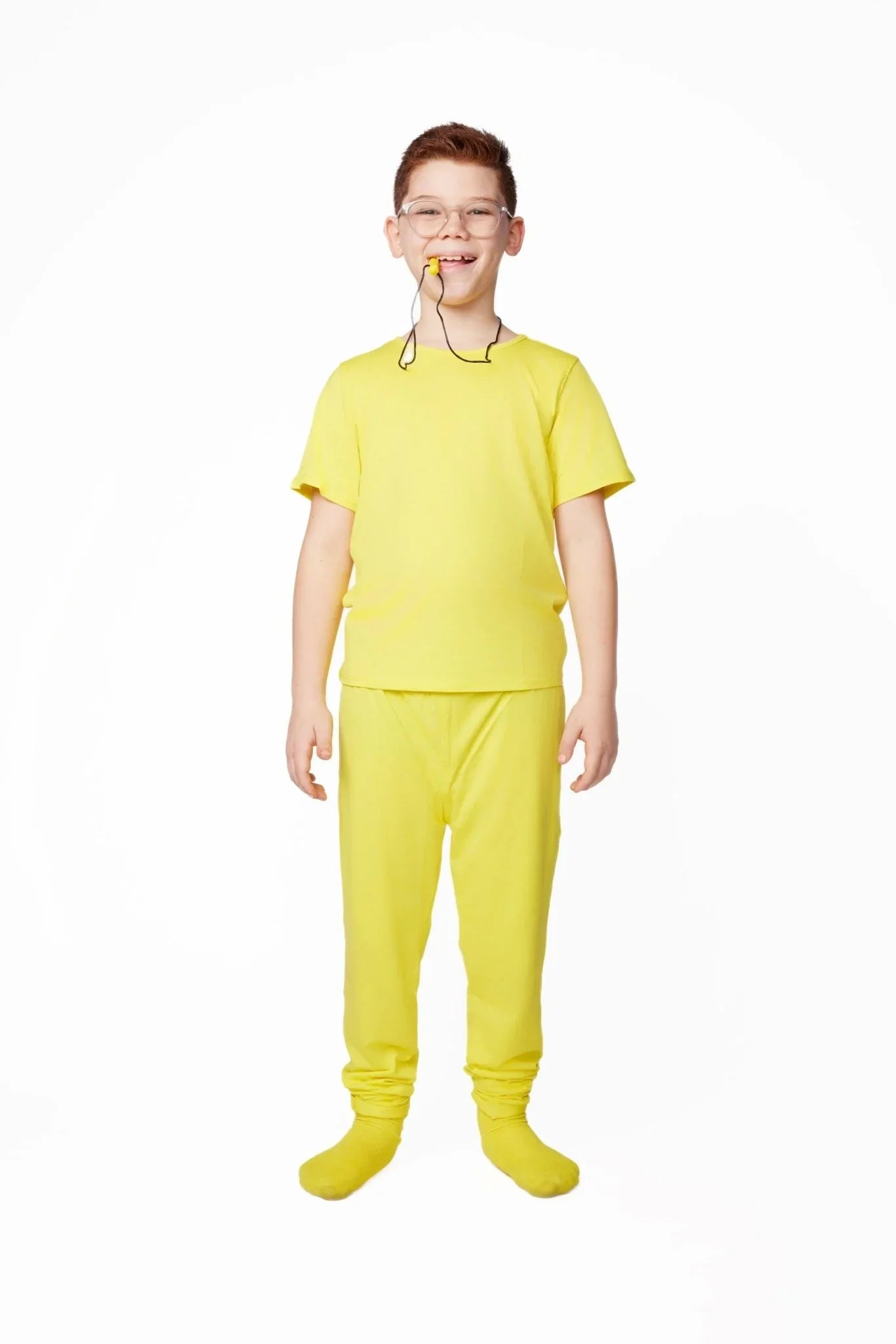 Child in yellow sensory-friendly clothing set with a chew necklace, standing and smiling