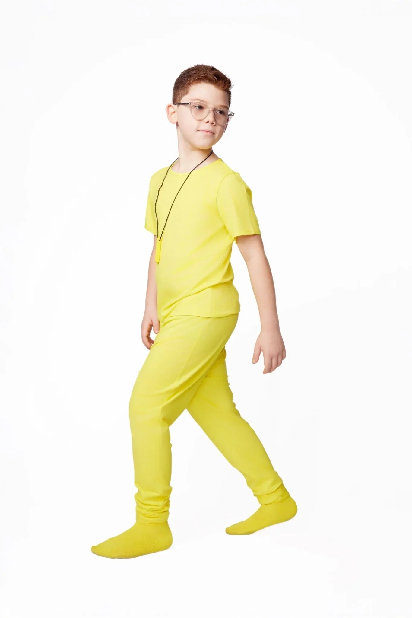 Child in yellow sensory-friendly clothing and glasses on white background
