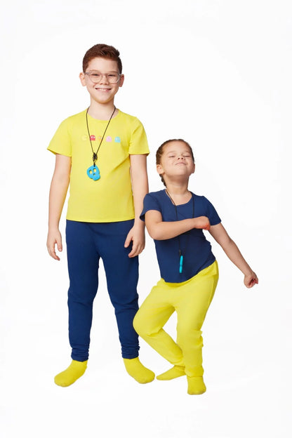 Two kids in sensory-friendly clothing with chewable necklaces, smiling against a white background.