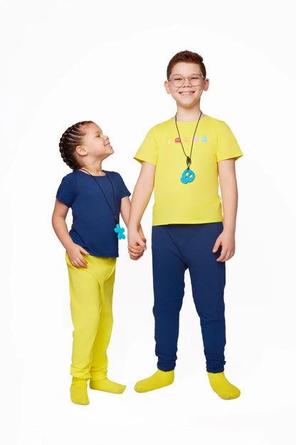 Two children in sensory-friendly clothing, wearing yellow and blue outfits and chewable necklaces