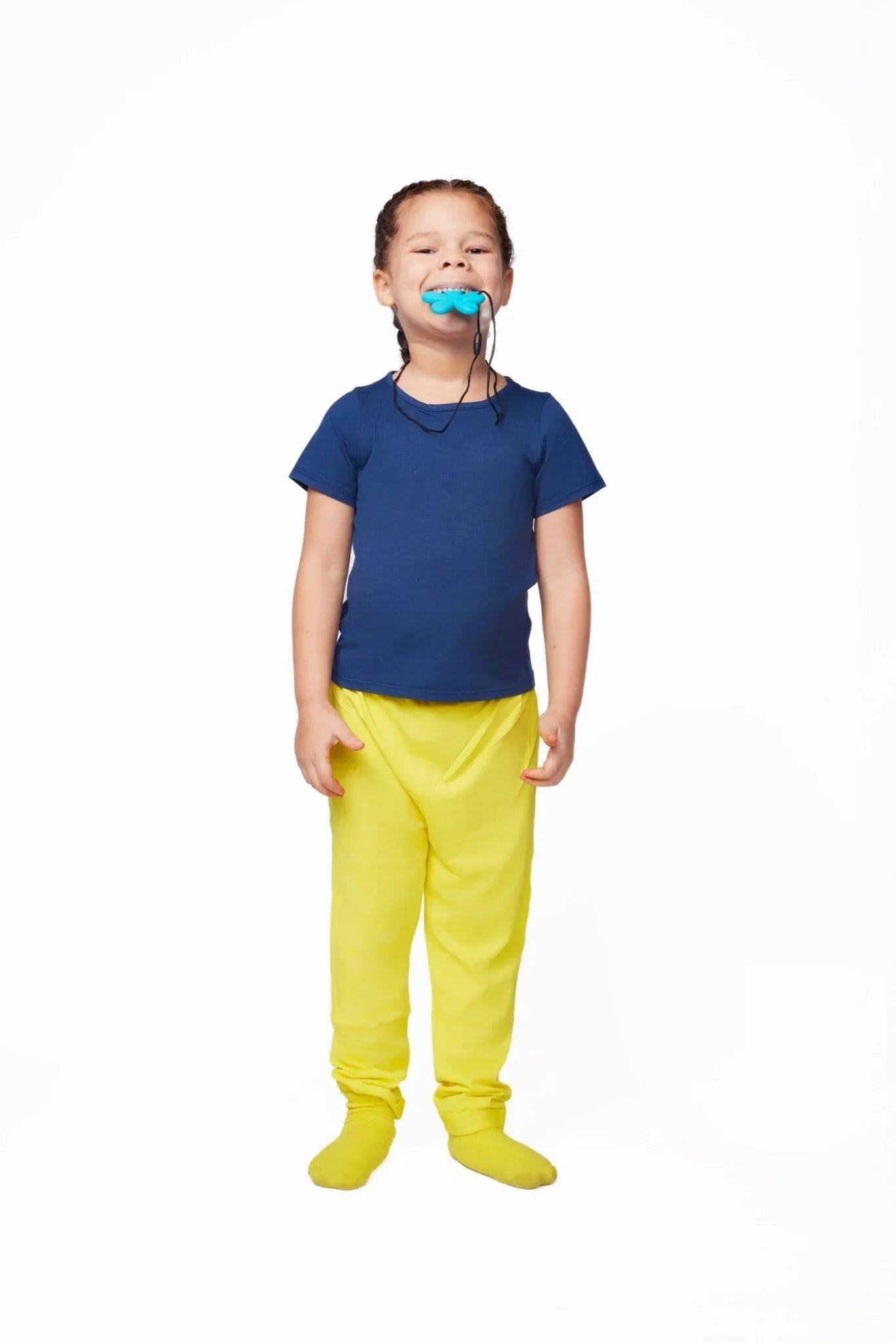 Child in sensory-friendly blue shirt and yellow pants using a chewable necklace
