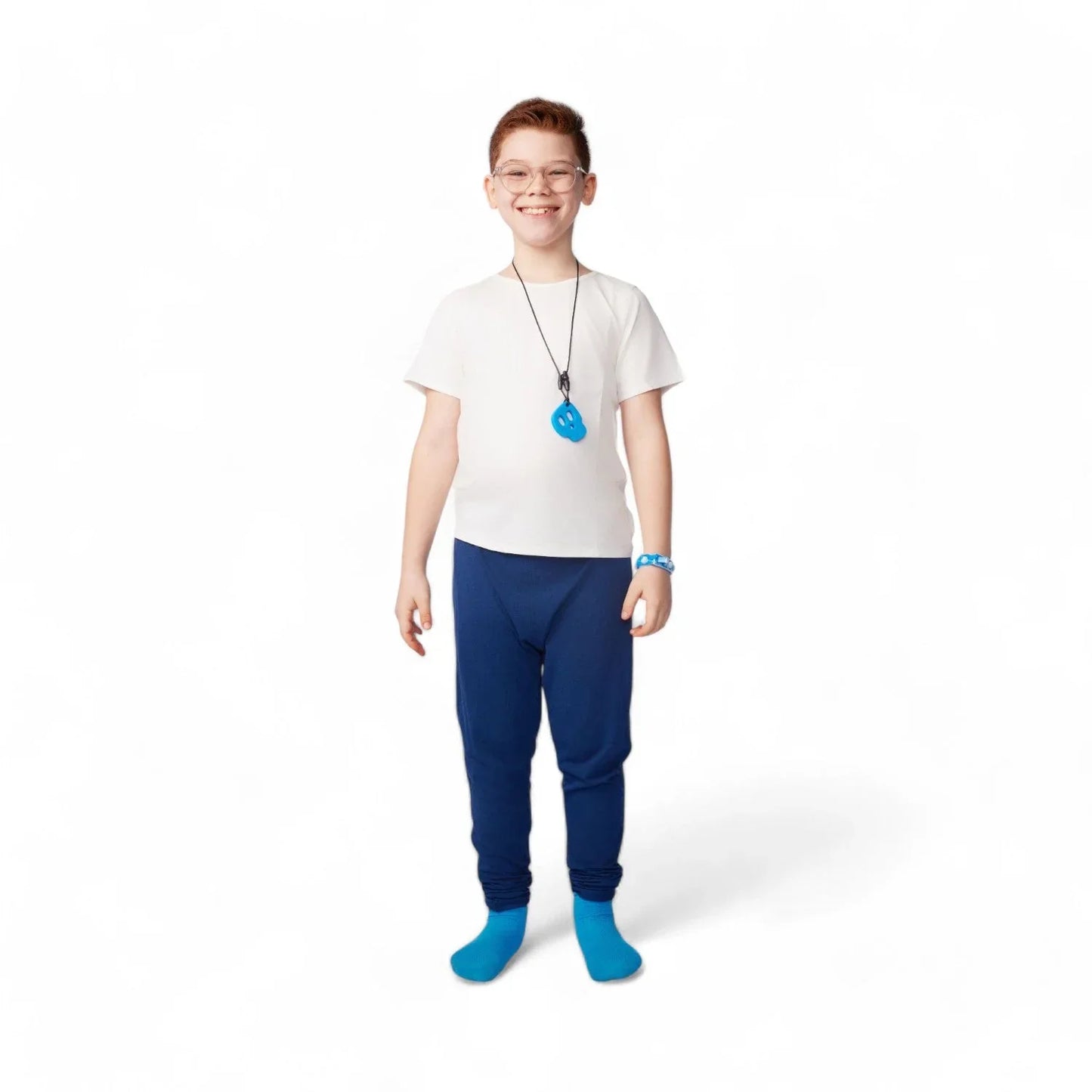 Smiling child wearing sensory-friendly clothing, blue sensory chew necklace, and blue pants