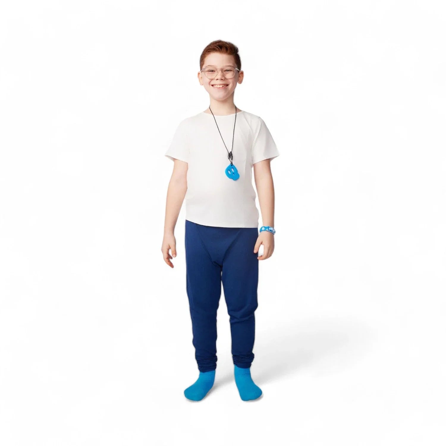Smiling child wearing sensory-friendly clothing, blue sensory chew necklace, and blue pants