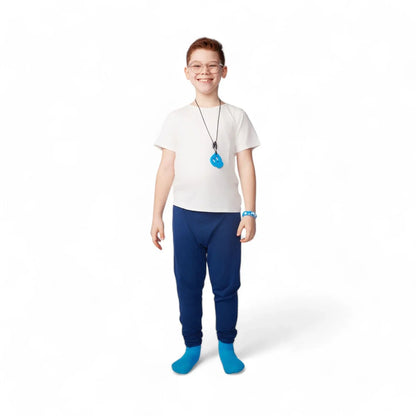 Smiling child wearing sensory-friendly clothing, blue sensory chew necklace, and blue pants
