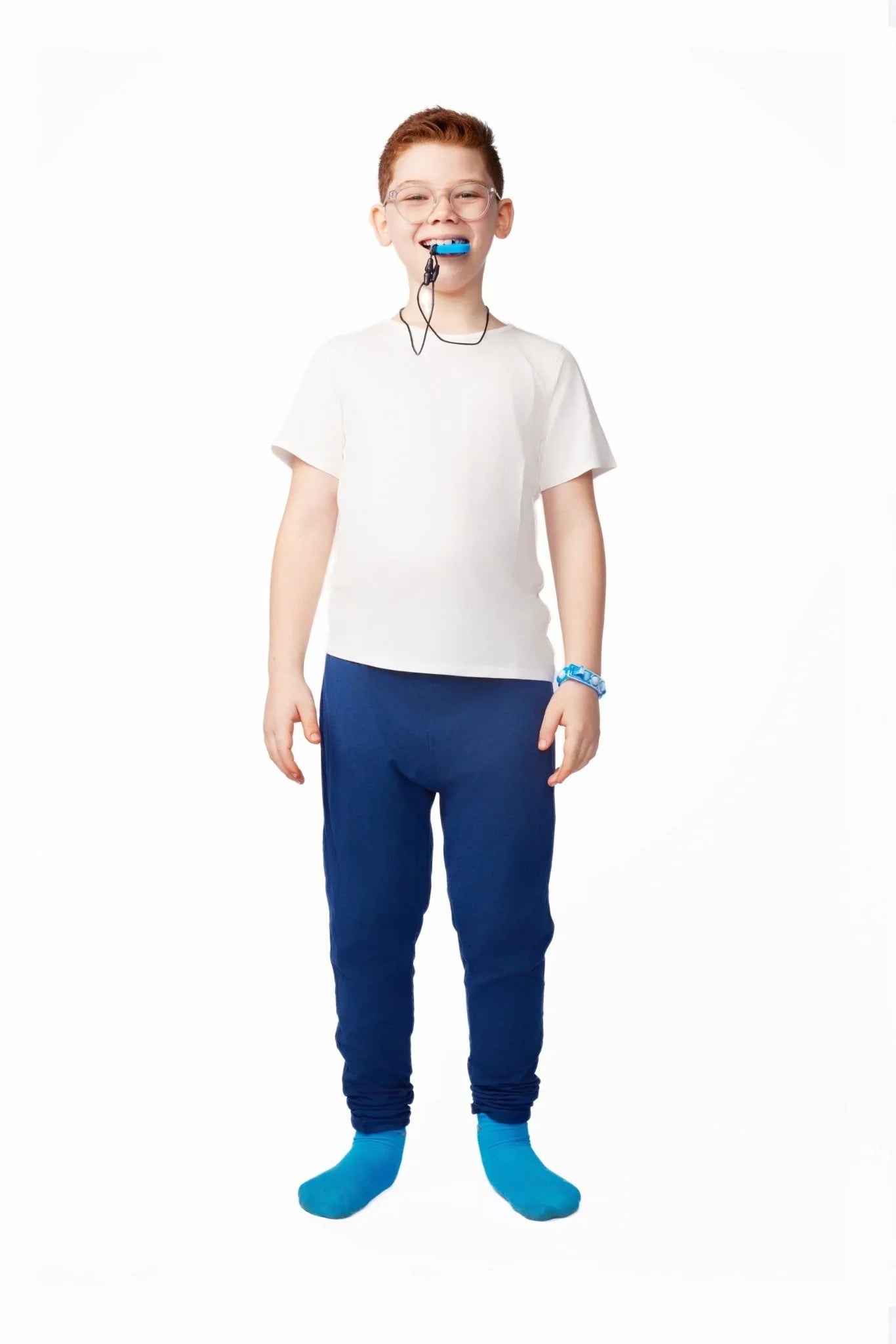 Smiling boy with glasses wearing sensory-friendly clothing, blue chew necklace, and blue socks