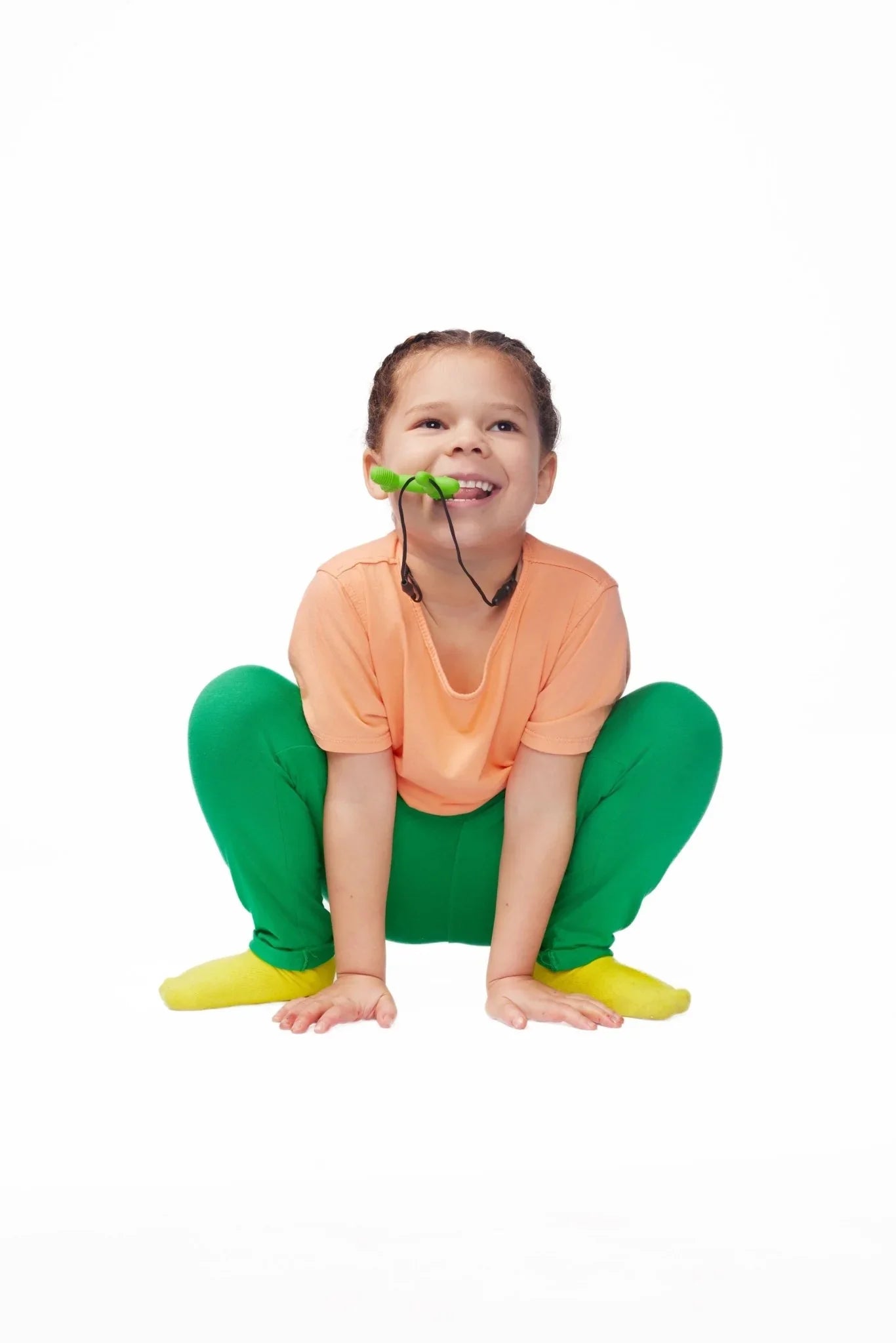 Child wearing sensory-friendly clothes chewing on green oral sensory chew necklace