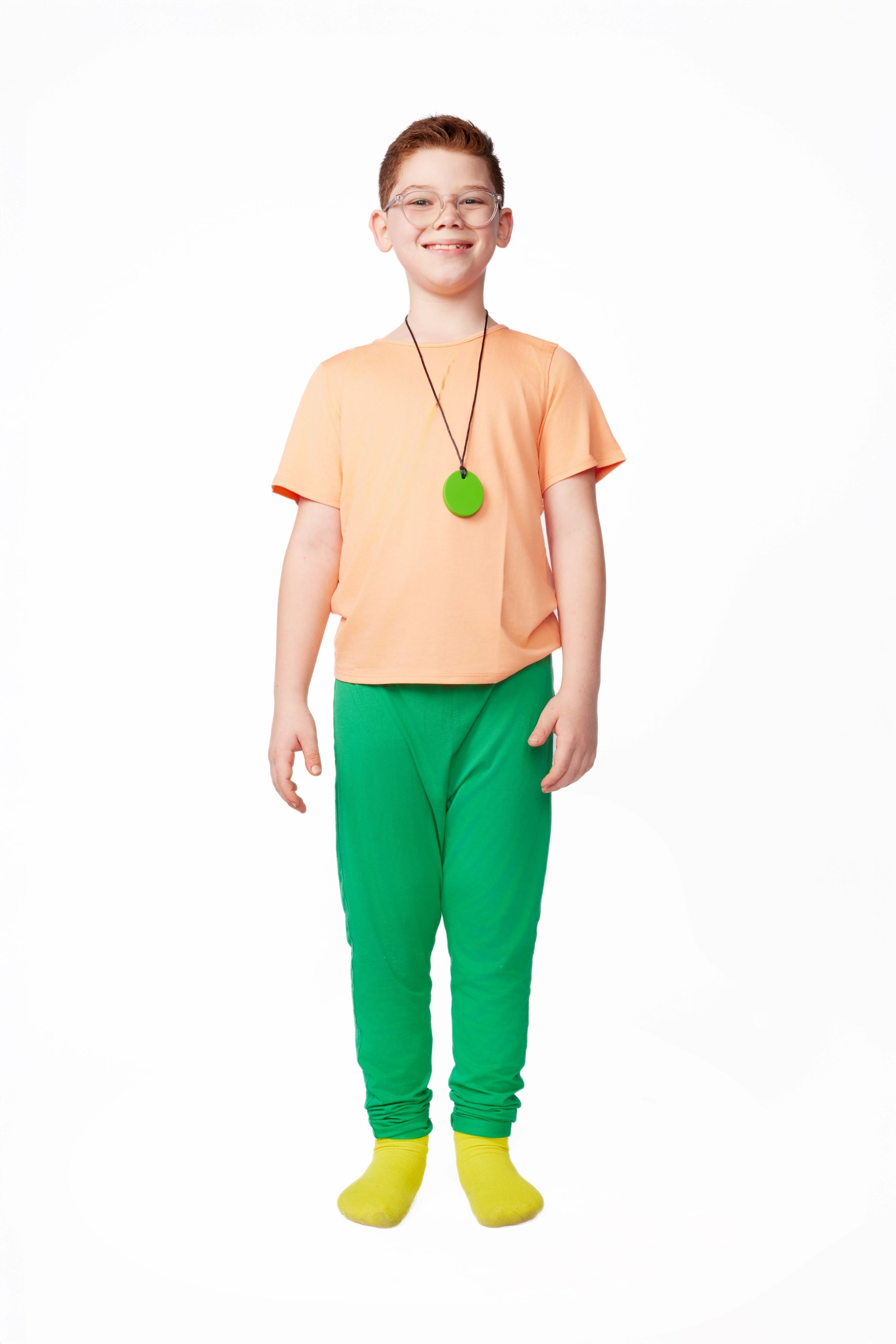 Child wearing an orange shirt, green pants, and yellow socks on a white background